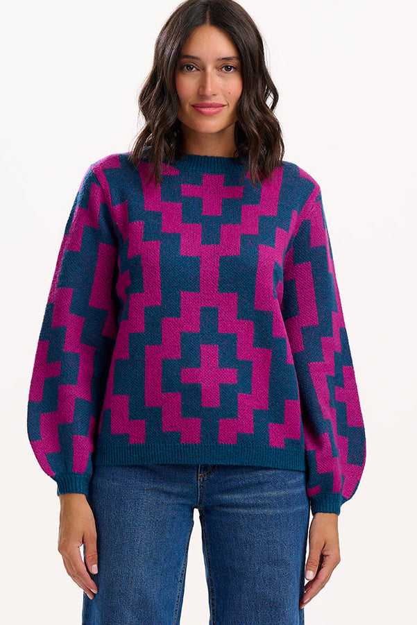 Woman wearing a patterned sweater and jeans on a white background