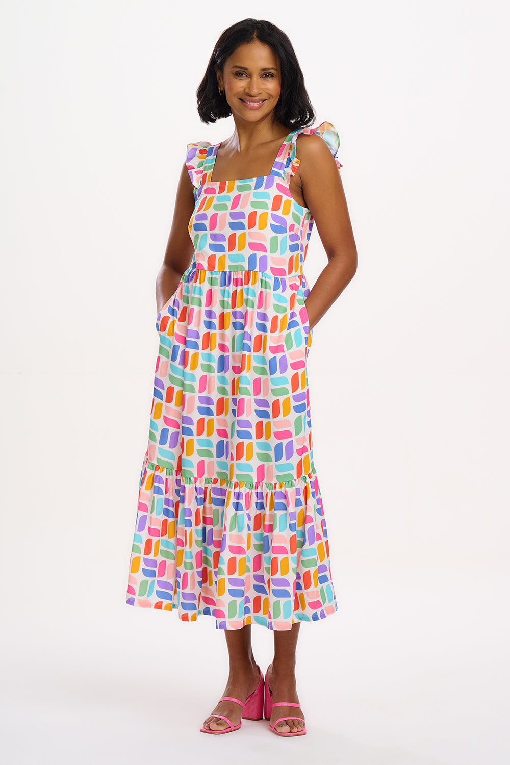 A model wearing an off-white midi sundress with a curved geometric print, featuring a shirred back panel and tiered skirt.