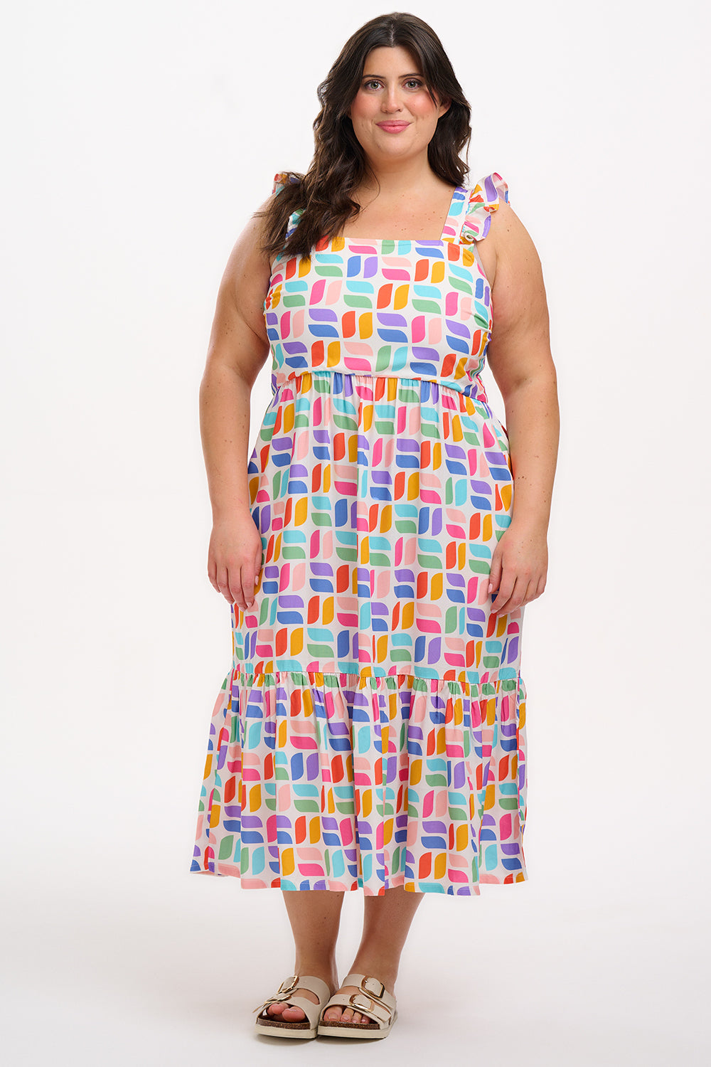 A model wearing an off-white midi sundress with a curved geometric print, featuring a shirred back panel and tiered skirt.