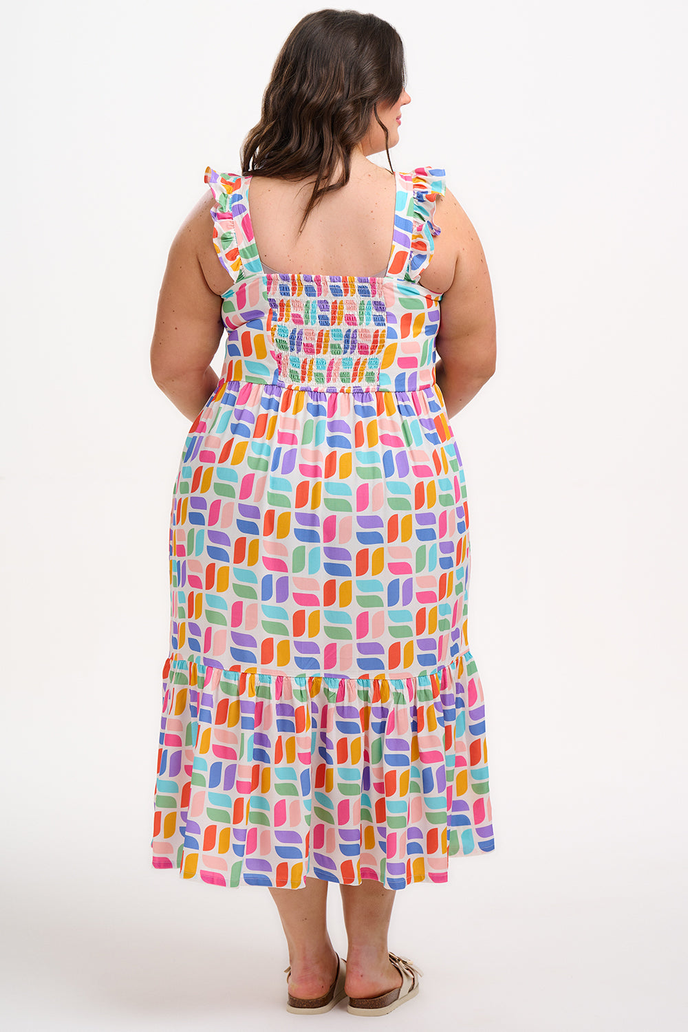 A model wearing an off-white midi sundress with a curved geometric print, featuring a shirred back panel and tiered skirt.