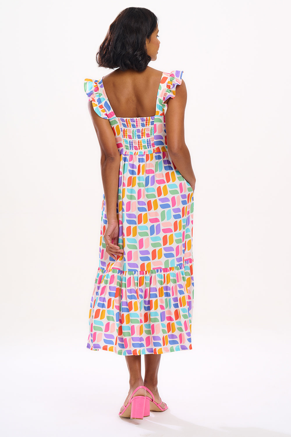 A model wearing an off-white midi sundress with a curved geometric print, featuring a shirred back panel and tiered skirt.