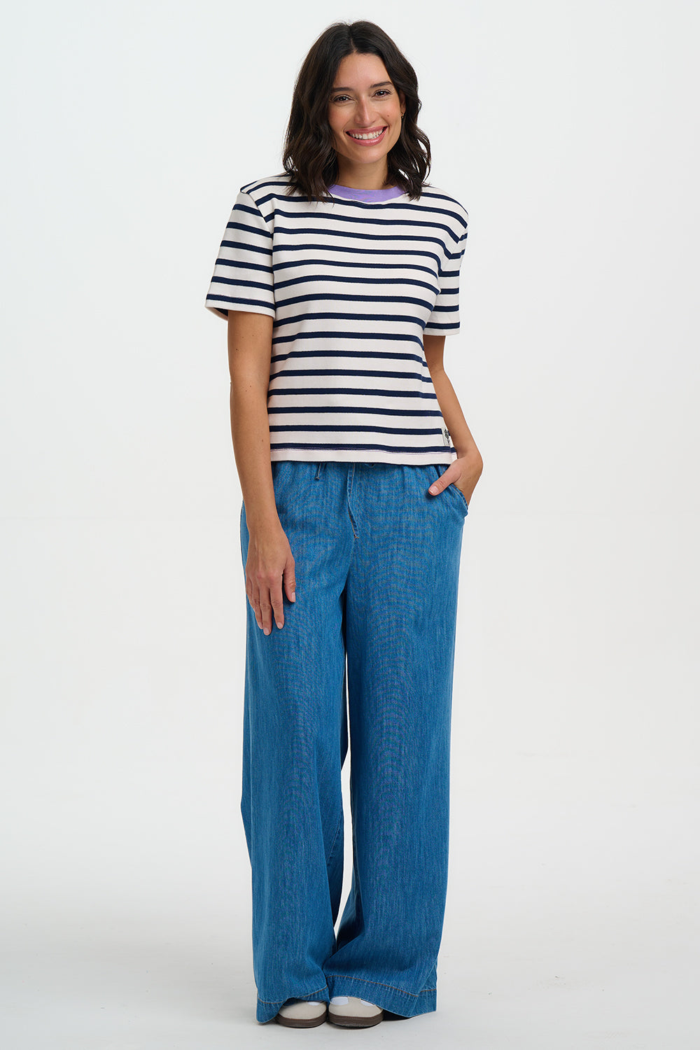 Woman wearing a striped shirt and blue pants on a white background