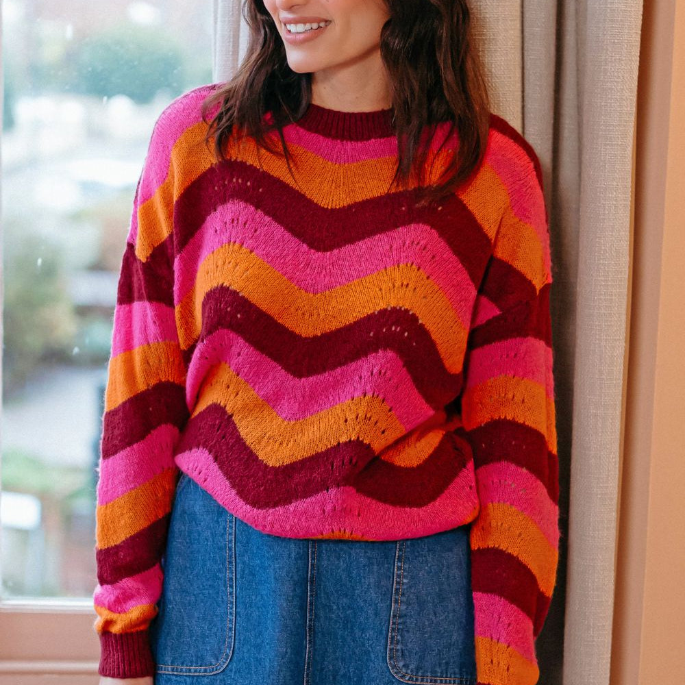 Woman wearing a colorful striped sweater standing indoors.