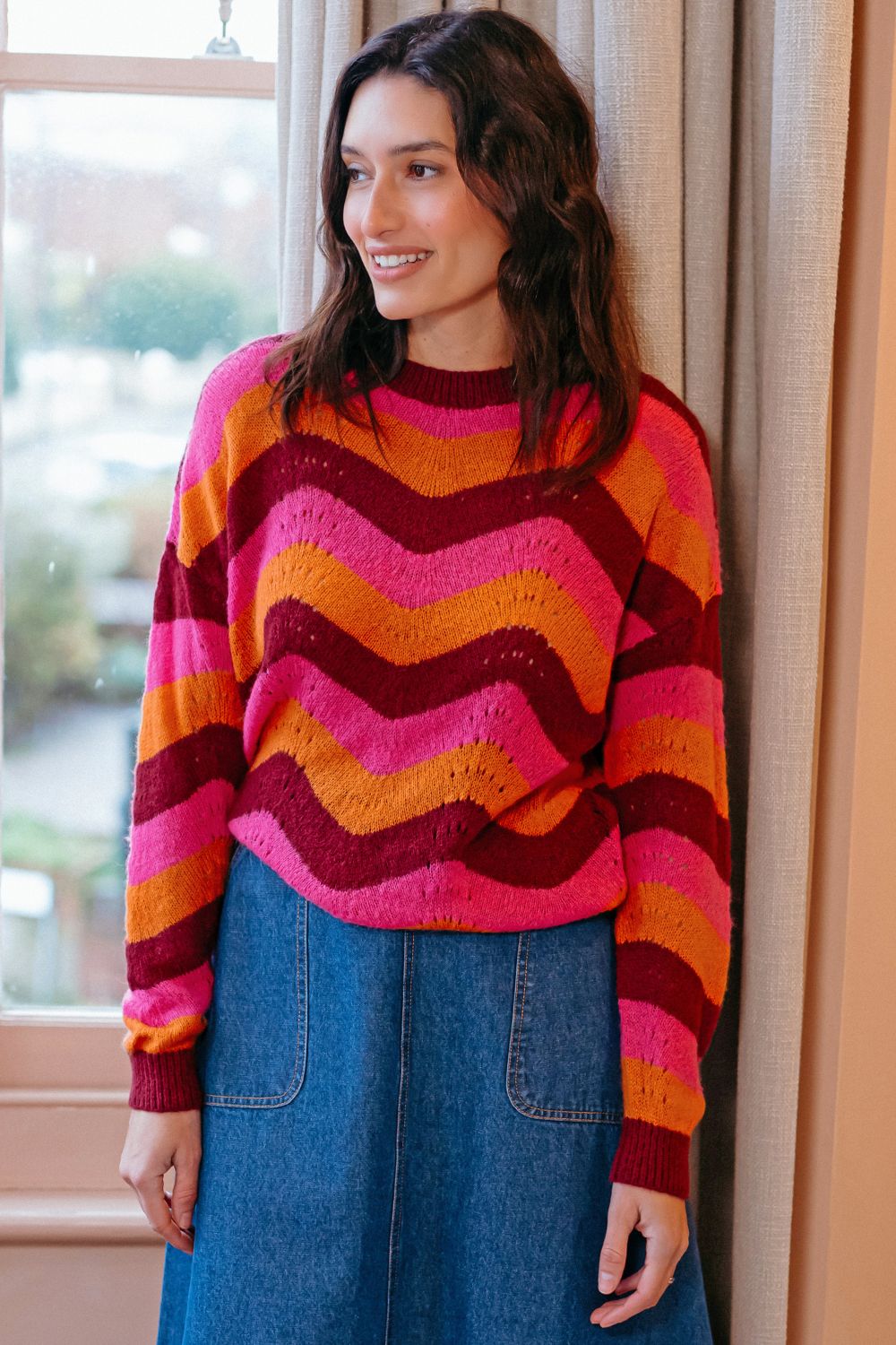 Woman wearing a colorful striped sweater standing indoors.