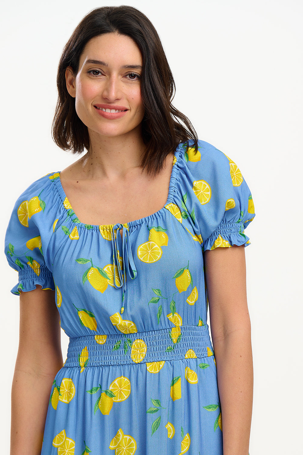 A woman modeling a midi dress with an off-the-shoulder neckline, featuring a blue color with yellow lemon print. The dress has frill-cuffed short sleeves and two front splits in the skirt.