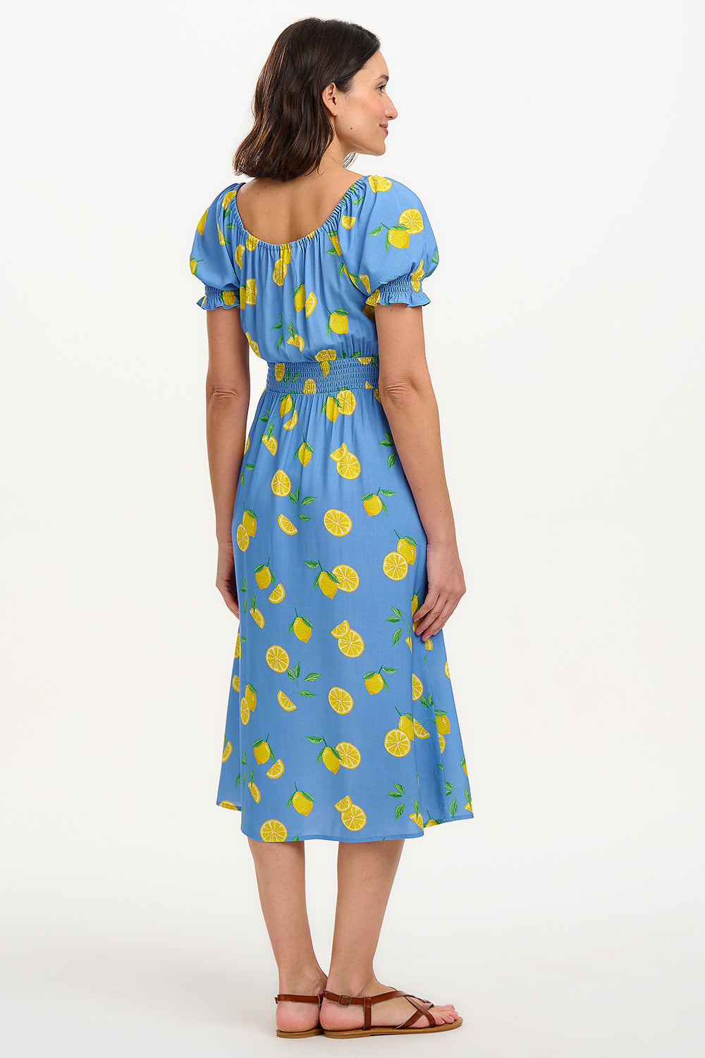 A woman modeling a midi dress with an off-the-shoulder neckline, featuring a blue color with yellow lemon print. The dress has frill-cuffed short sleeves and two front splits in the skirt.