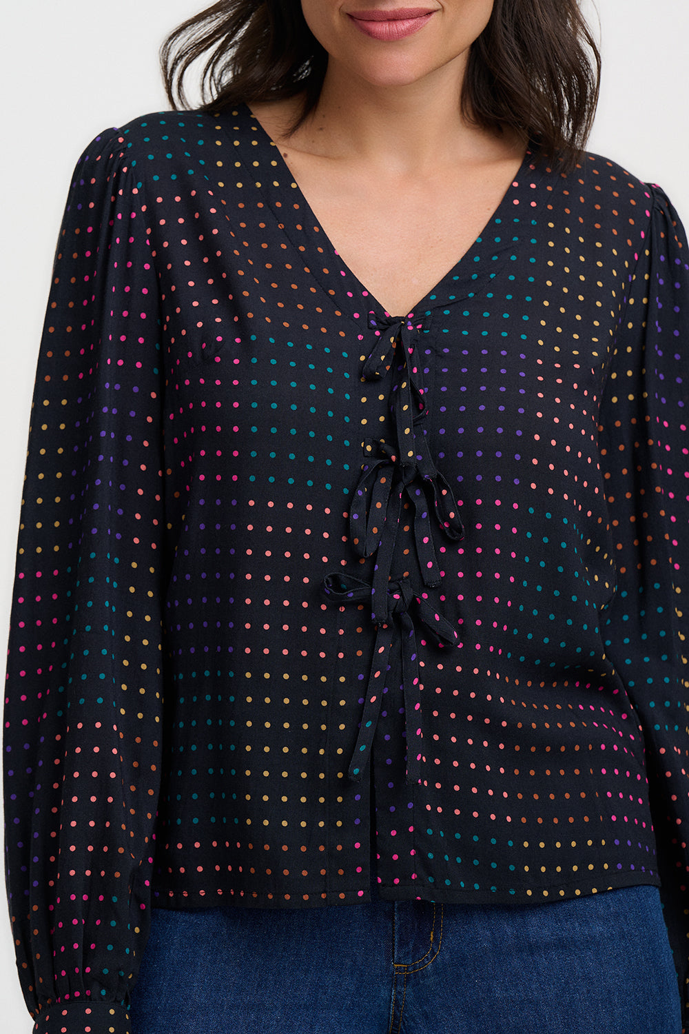 Woman wearing a dark blue blouse with colorful polka dot pattern on a white background