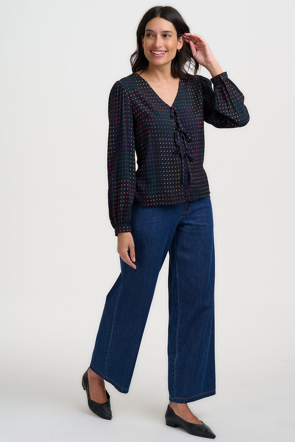 Woman wearing a patterned blouse and blue pants on a white background