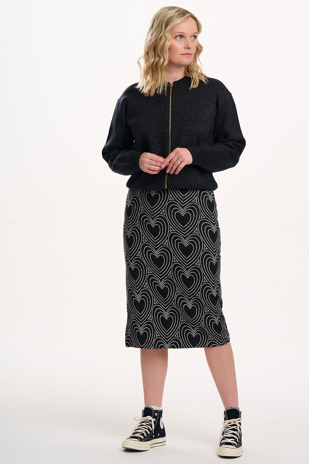 Woman wearing a black sweater and patterned skirt on a white background