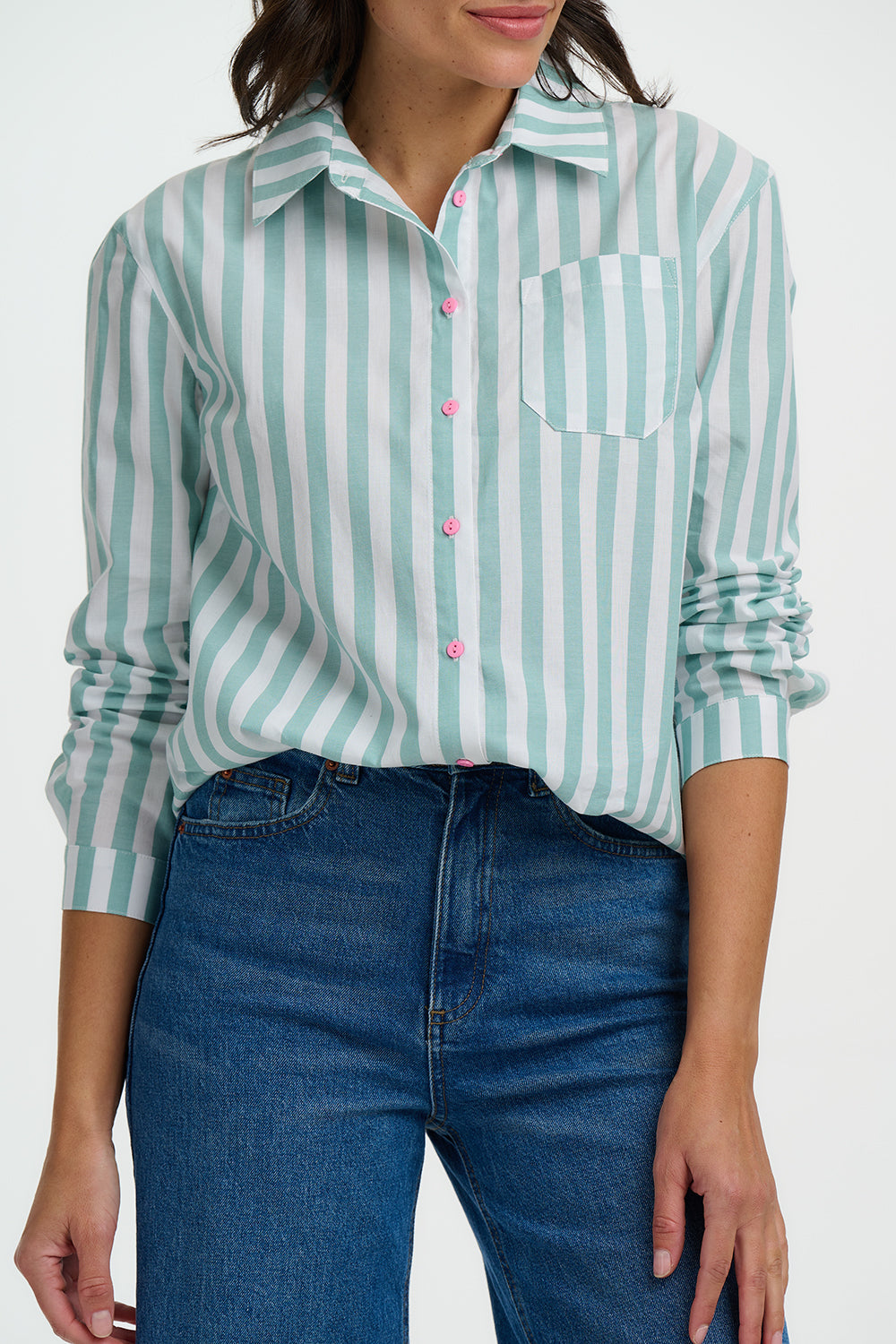 Woman wearing a green and white striped shirt with blue jeans on a white background
