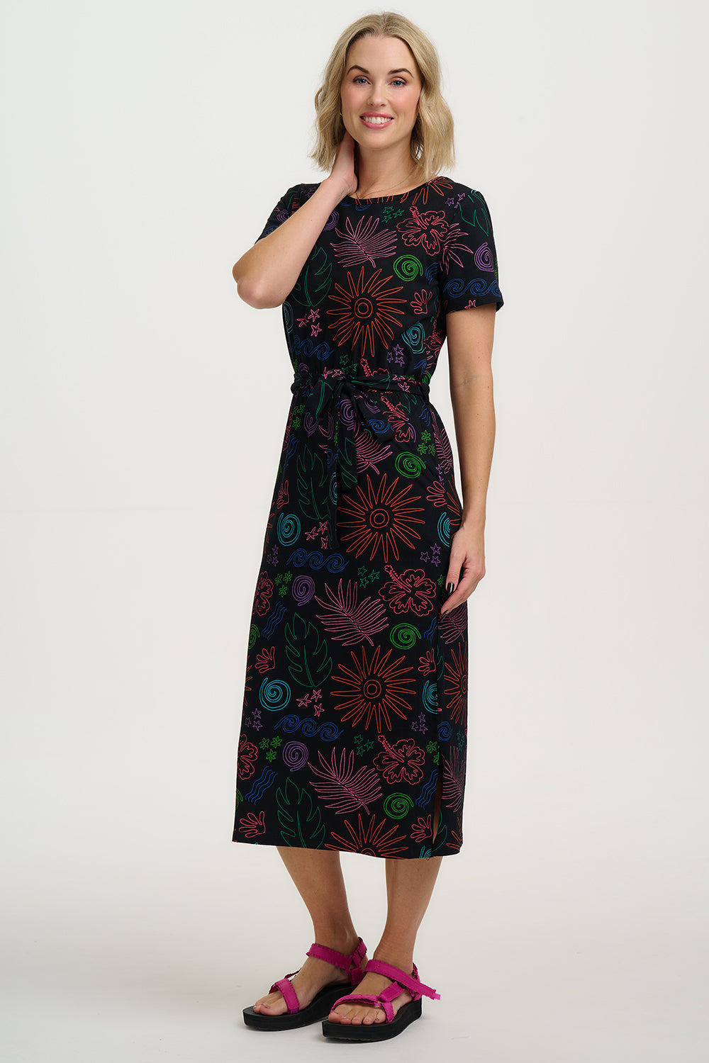 Woman wearing a black dress with colorful floral patterns on a white background