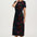 Woman wearing a black dress with colorful floral patterns on a white background