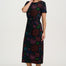 Woman wearing a black dress with colorful floral patterns on a white background
