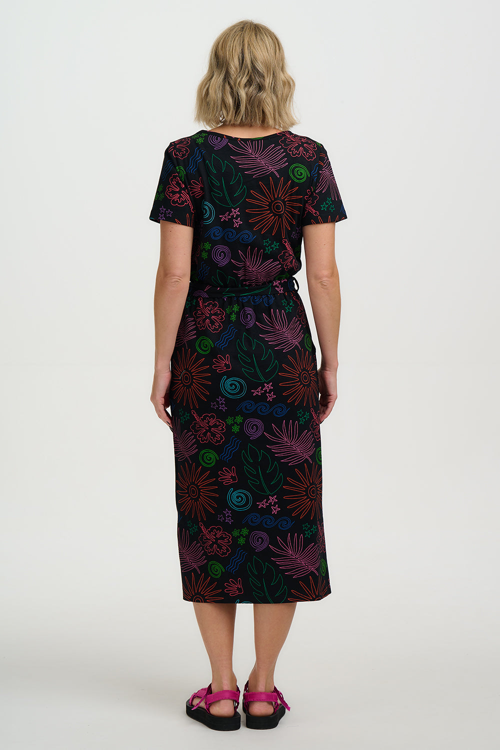 Woman wearing a black dress with colorful abstract patterns on a white background