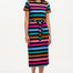 A model wearing a midi length, short sleeve, striped dress in black and multiple colors with a belt, standing against a white background.