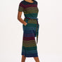 A model wearing a midi-length jersey dress with a black background featuring a vibrant multicolour striped pattern. The dress has a t-shirt fit with a matching tie belt and short sleeves.