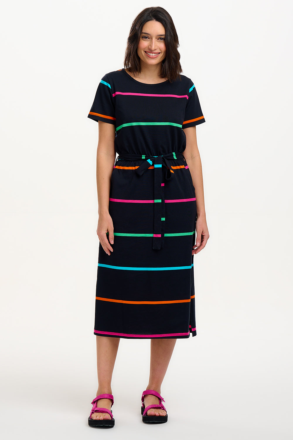 A model wearing a midi-length black dress with vibrant colored stripes, featuring a matching tie belt and short sleeves.