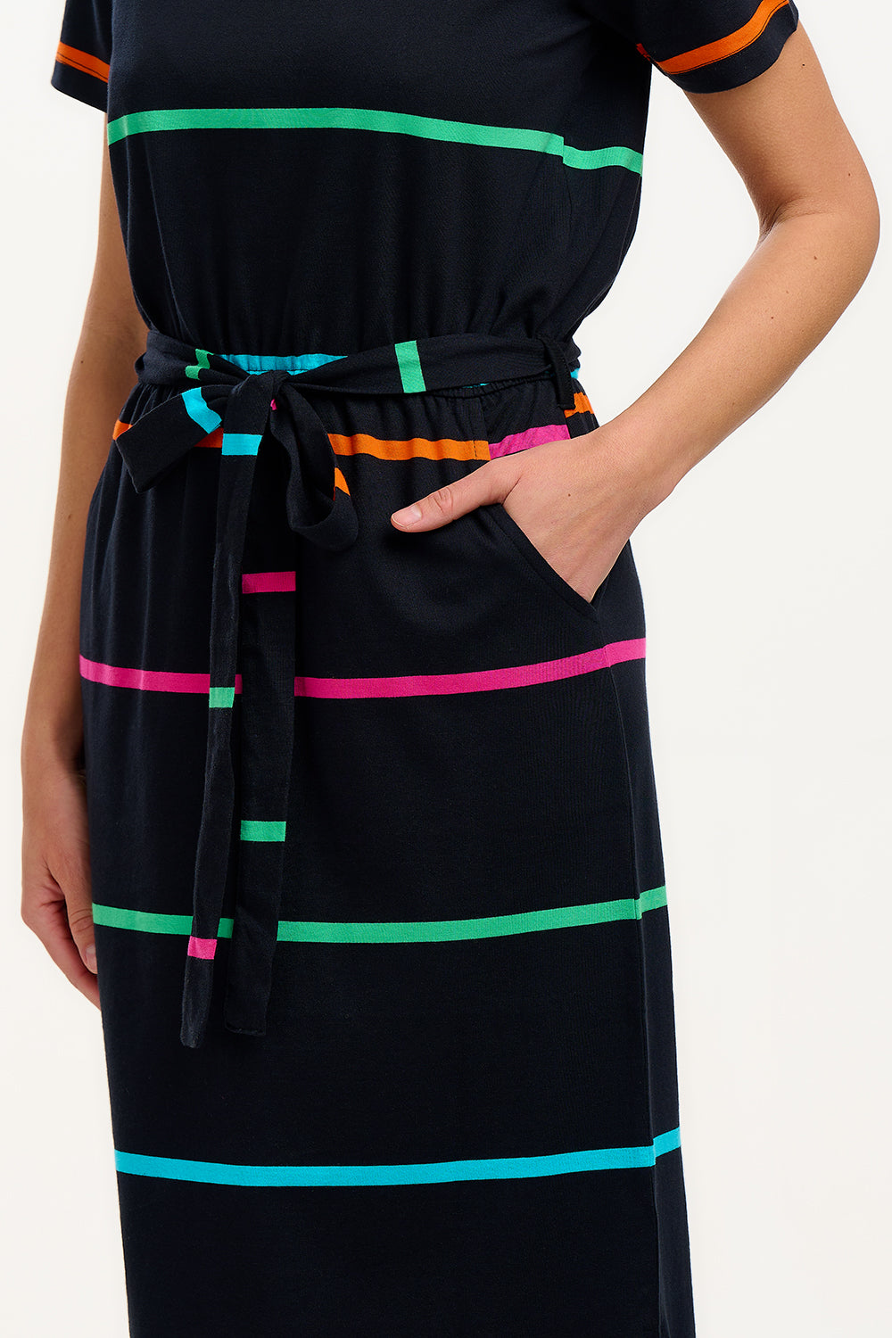 A model wearing a midi-length black dress with vibrant colored stripes, featuring a matching tie belt and short sleeves.