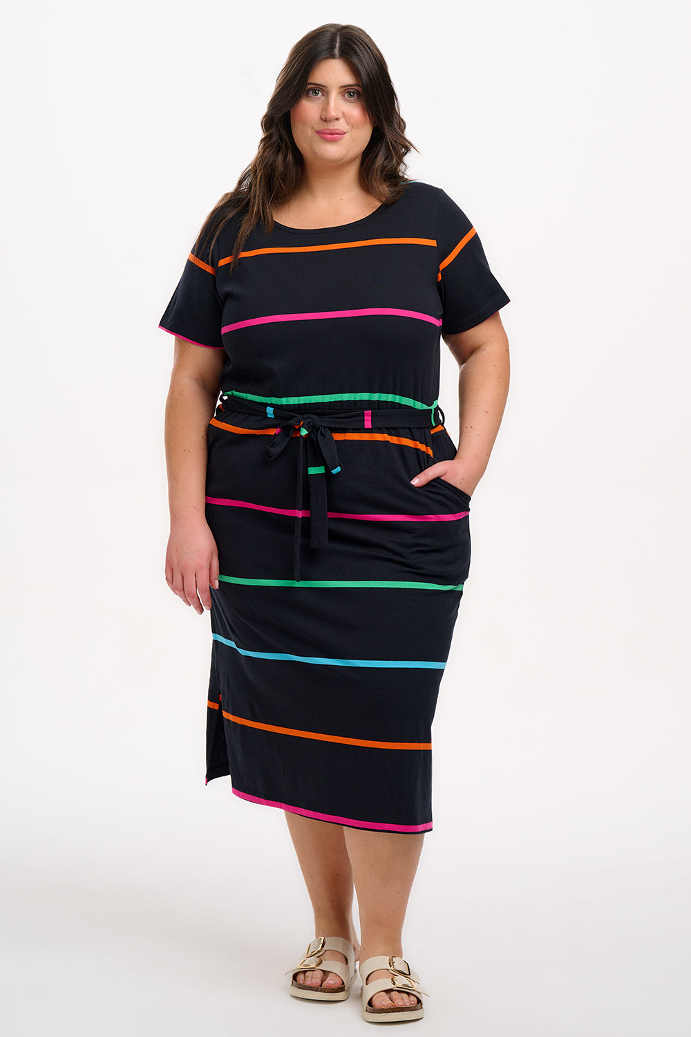 A model wearing a midi-length black dress with vibrant colored stripes, featuring a matching tie belt and short sleeves.