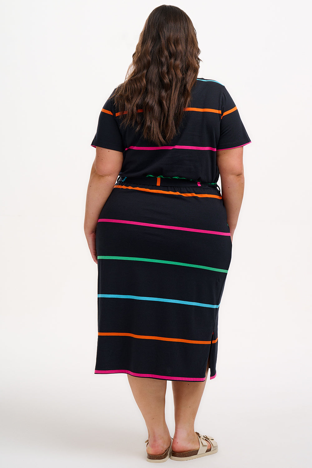 A model wearing a midi-length black dress with vibrant colored stripes, featuring a matching tie belt and short sleeves.