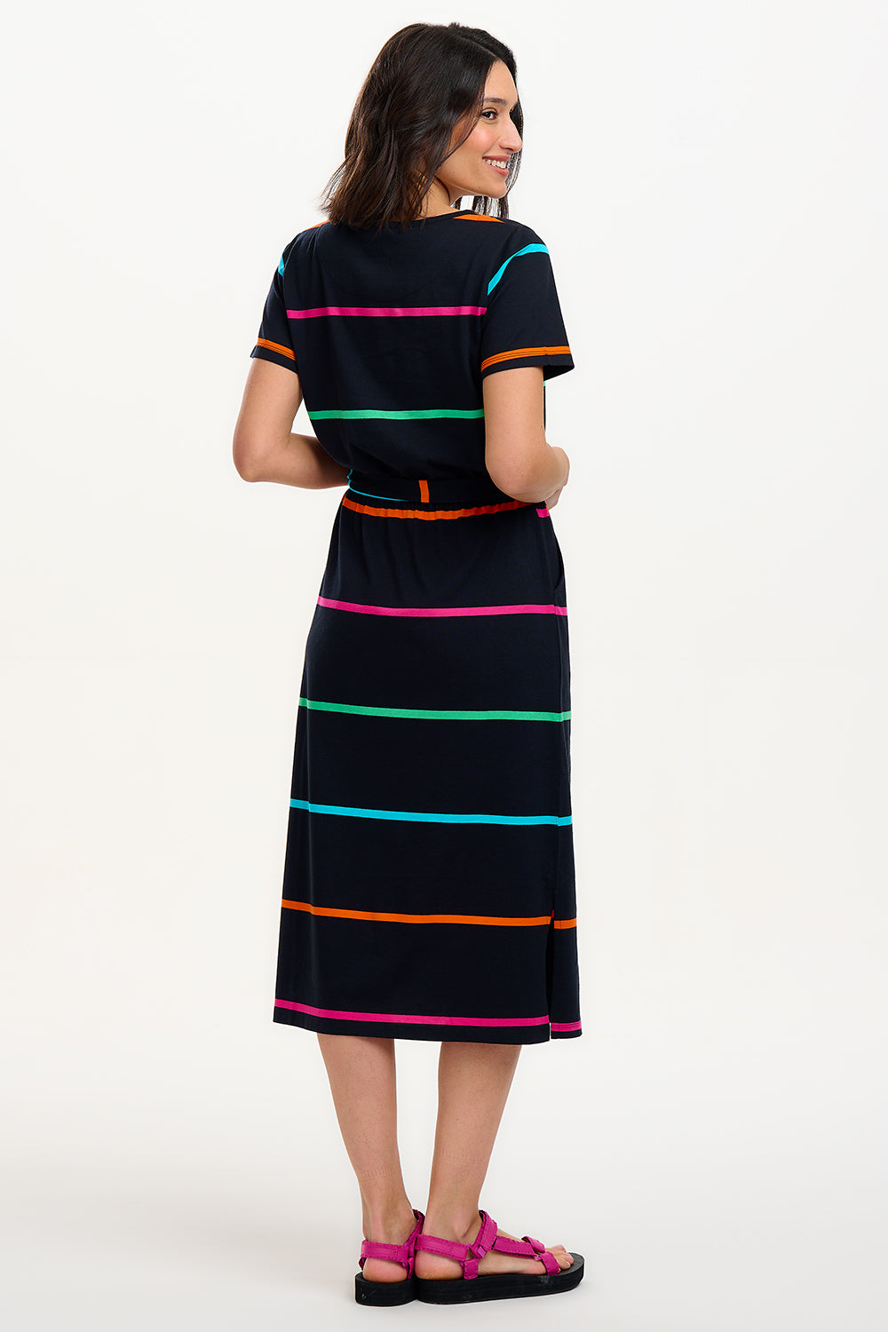 A model wearing a midi-length black dress with vibrant colored stripes, featuring a matching tie belt and short sleeves.