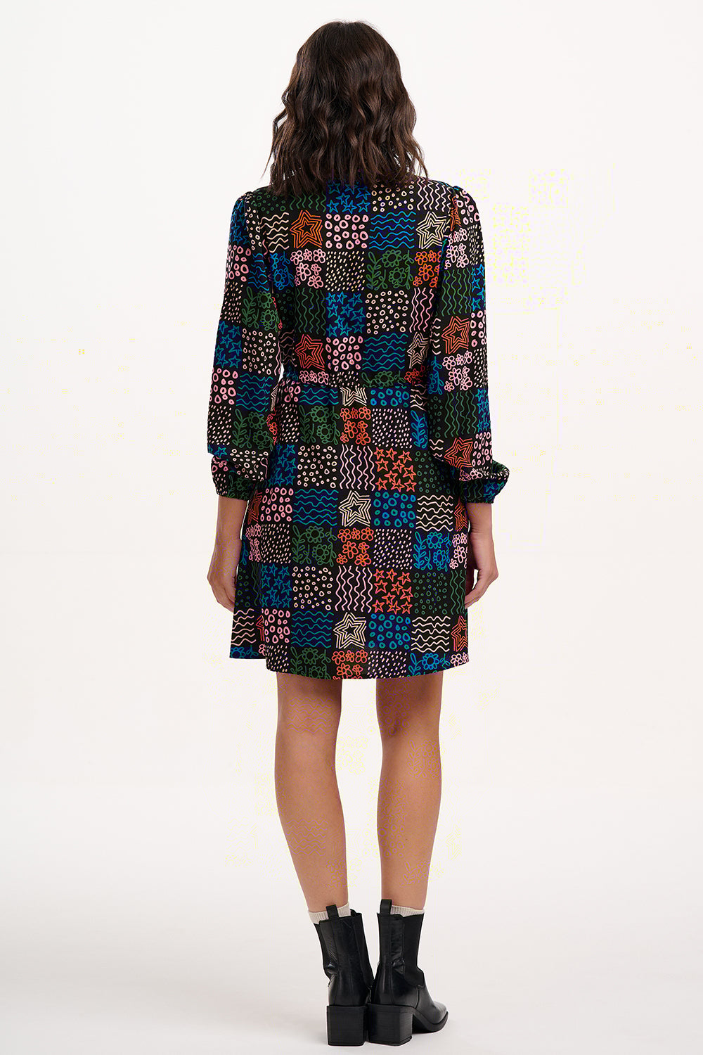 Person wearing a colorful patterned dress on a white background