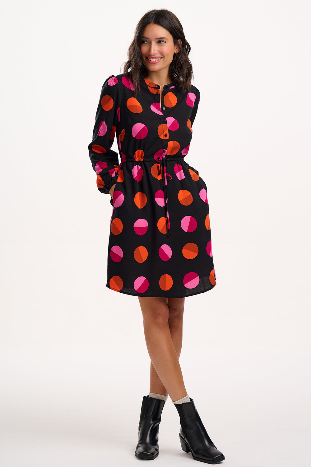 Woman wearing a black dress with colorful polka dots on a white background