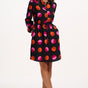 Woman wearing a black dress with colorful polka dots on a white background