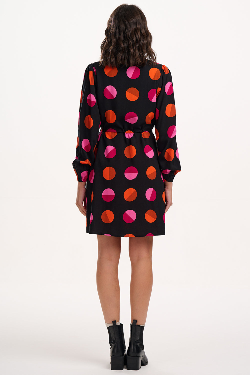 Woman wearing a black dress with colorful polka dot pattern on a white background