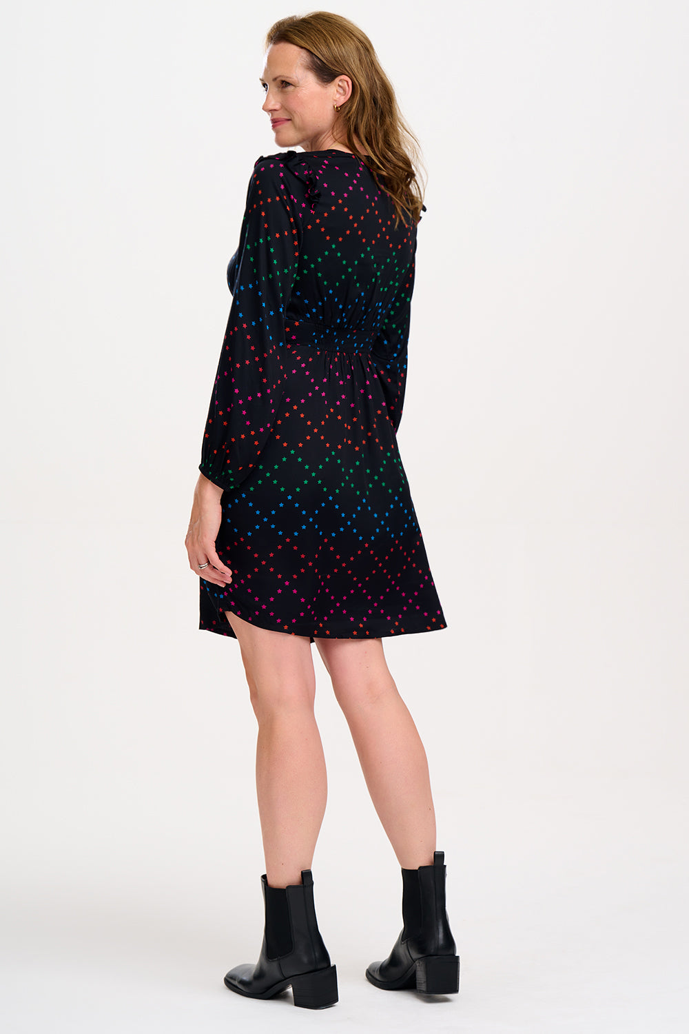 Woman wearing a black dress with colorful polka dots.