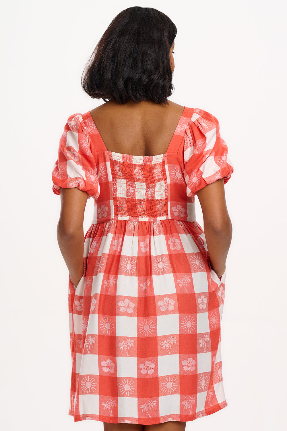 A woman wearing an off-white and coral gingham mini dress with puff sleeves and a tailored waist.