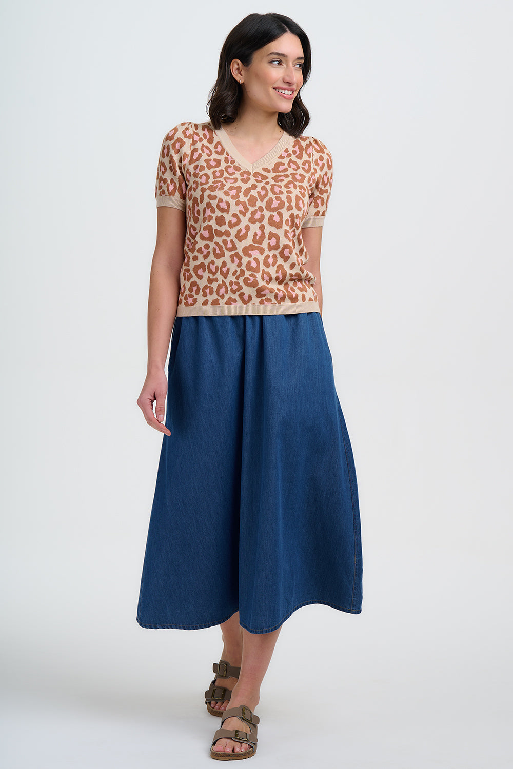 Woman wearing a leopard print top and blue skirt on a white background