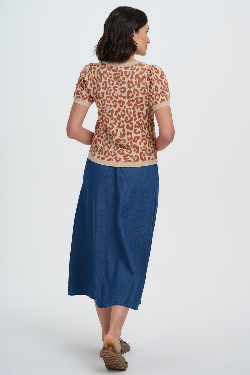 Woman wearing a leopard print top and blue skirt on a white background