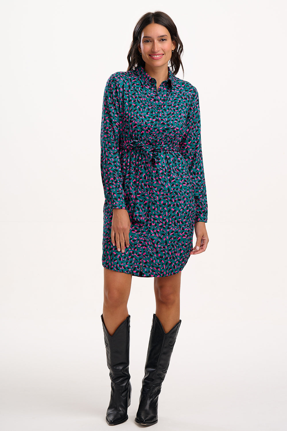 Woman wearing a patterned dress with long sleeves and black boots on a white background
