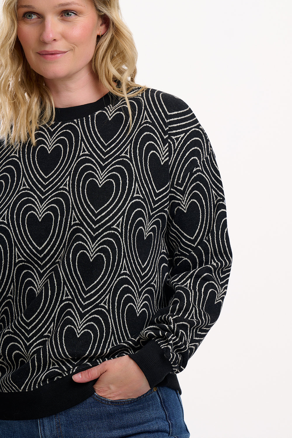 Woman wearing a black sweater with white heart pattern on a white background