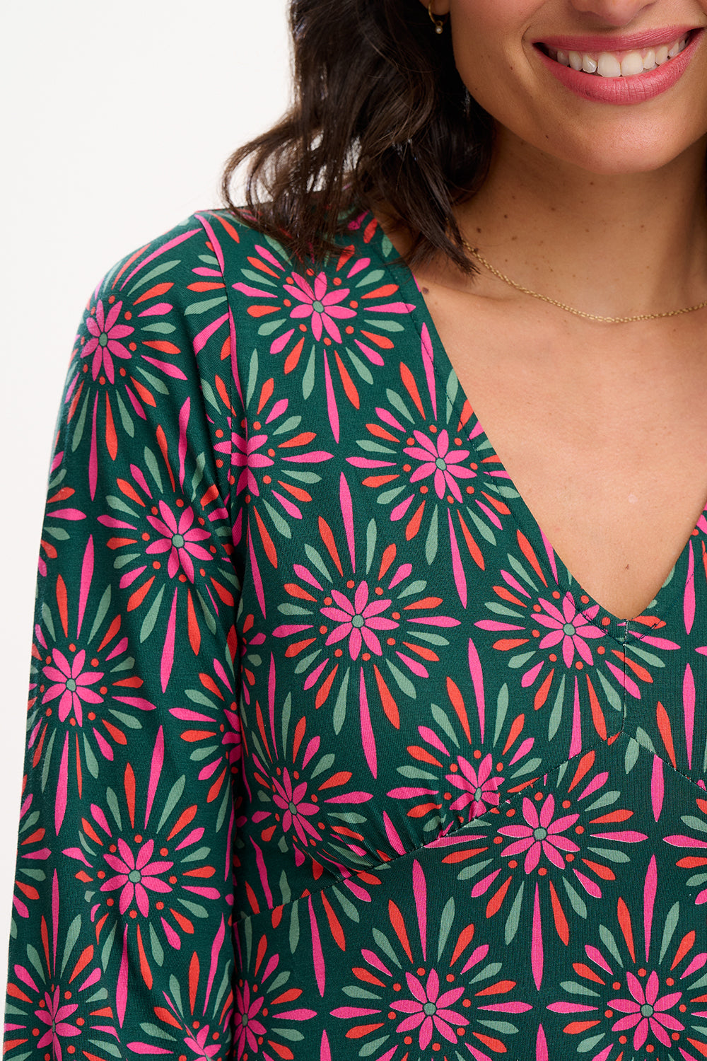 Sugarhill Brighton model wearing a green dress with pink floral pattern on a white background