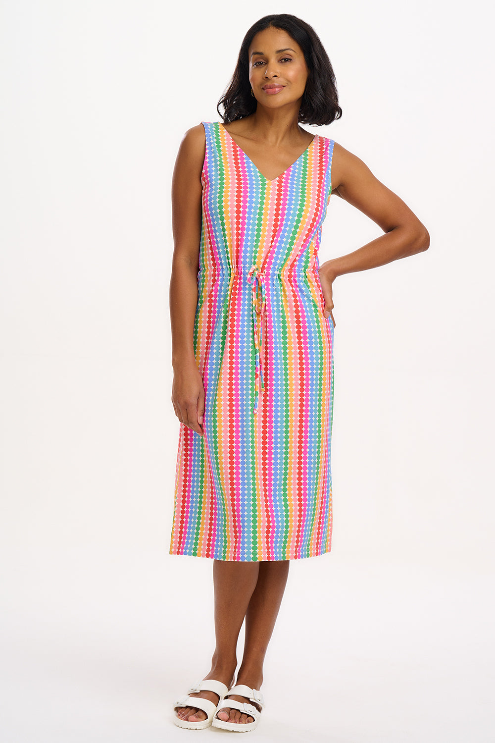 A model wearing a sleeveless, knee-length multicolored dress with a V-neck front and a drawstring waist.