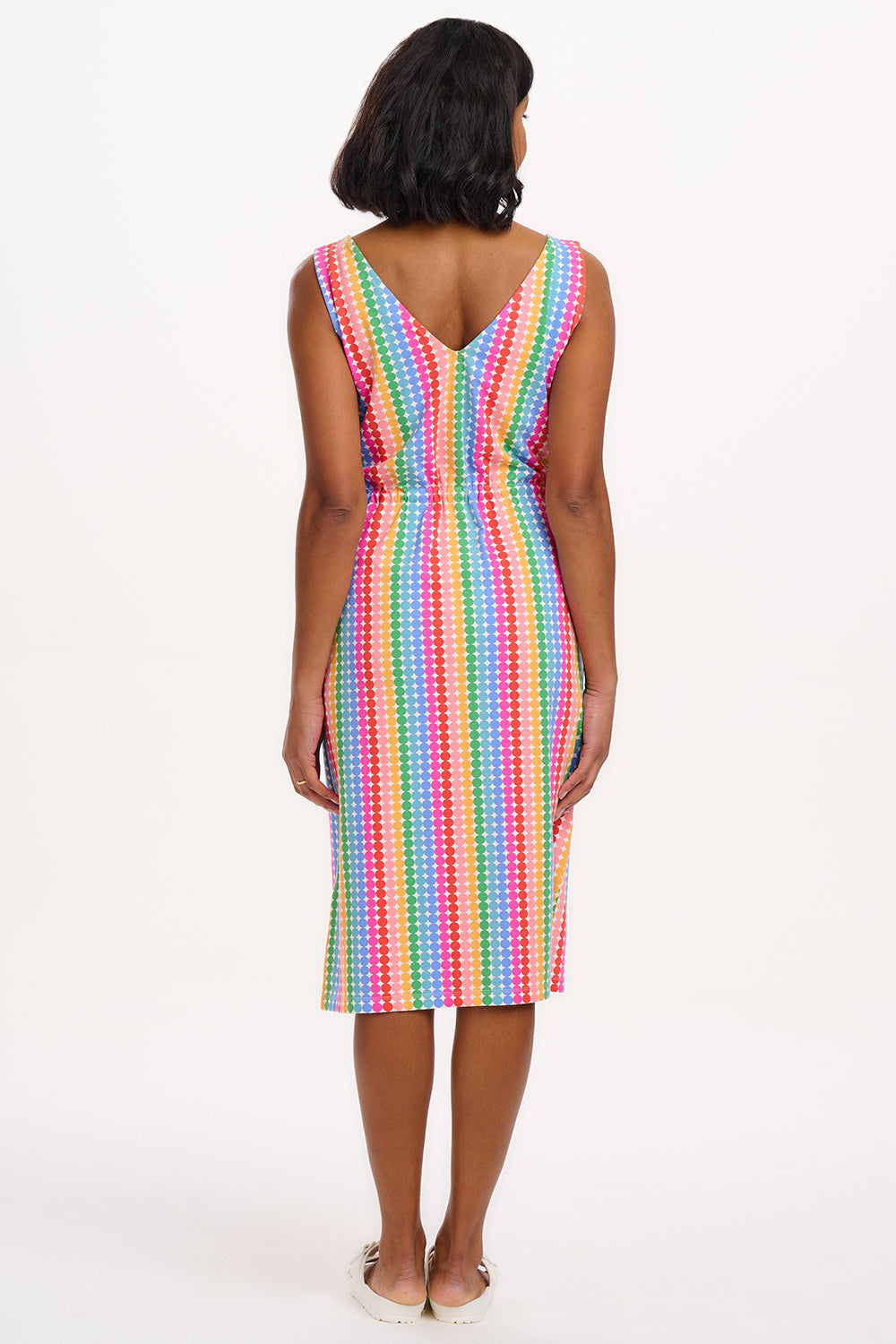 A model wearing a sleeveless, knee-length multicolored dress with a V-neck front and a drawstring waist.
