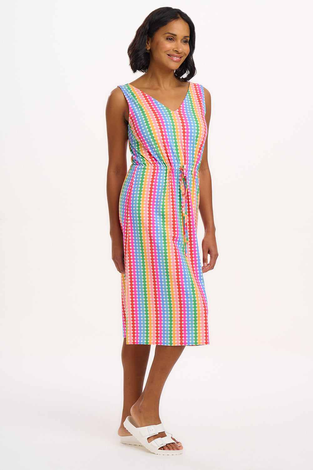 A model wearing a sleeveless, knee-length multicolored dress with a V-neck front and a drawstring waist.