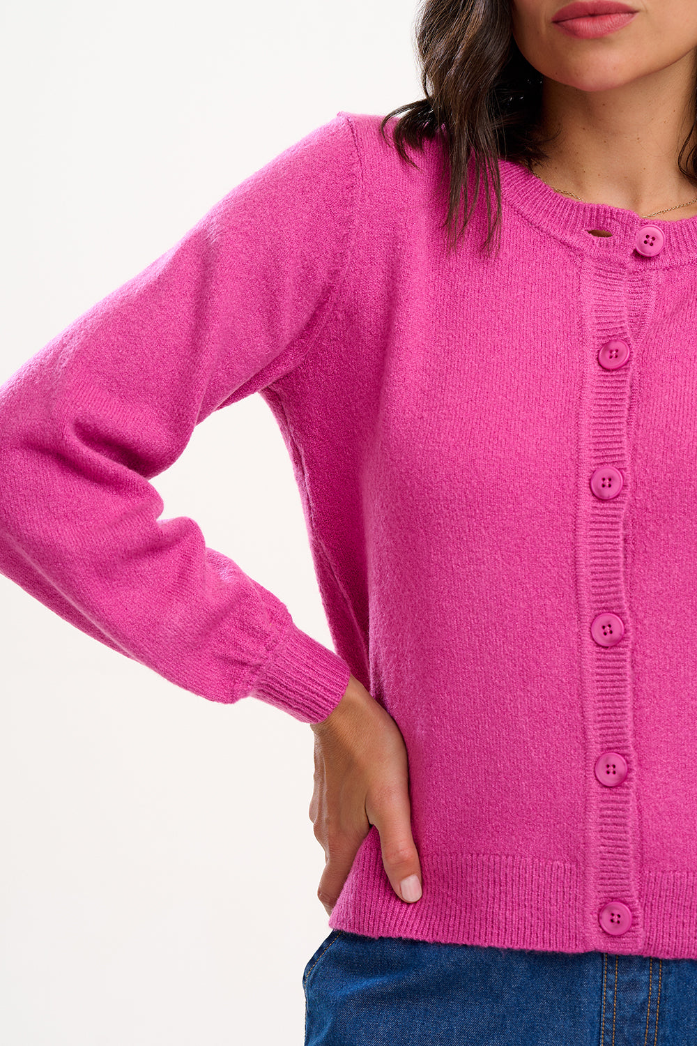 Sugarhill Brighton model wearing a bright pink cardigan with buttons on a white background