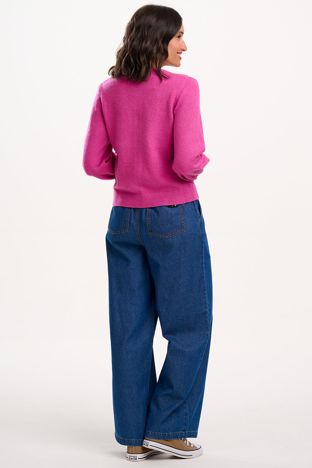 Suagrhill Brighton model wearing a pink sweater and blue jeans on a white background