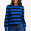 Woman wearing a blue and black striped sweater with jeans on a white background