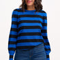 Woman wearing a blue and black striped sweater with jeans on a white background
