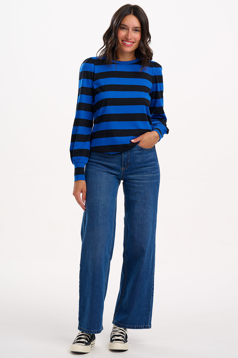 Woman wearing a blue and black striped sweater with blue jeans on a white background