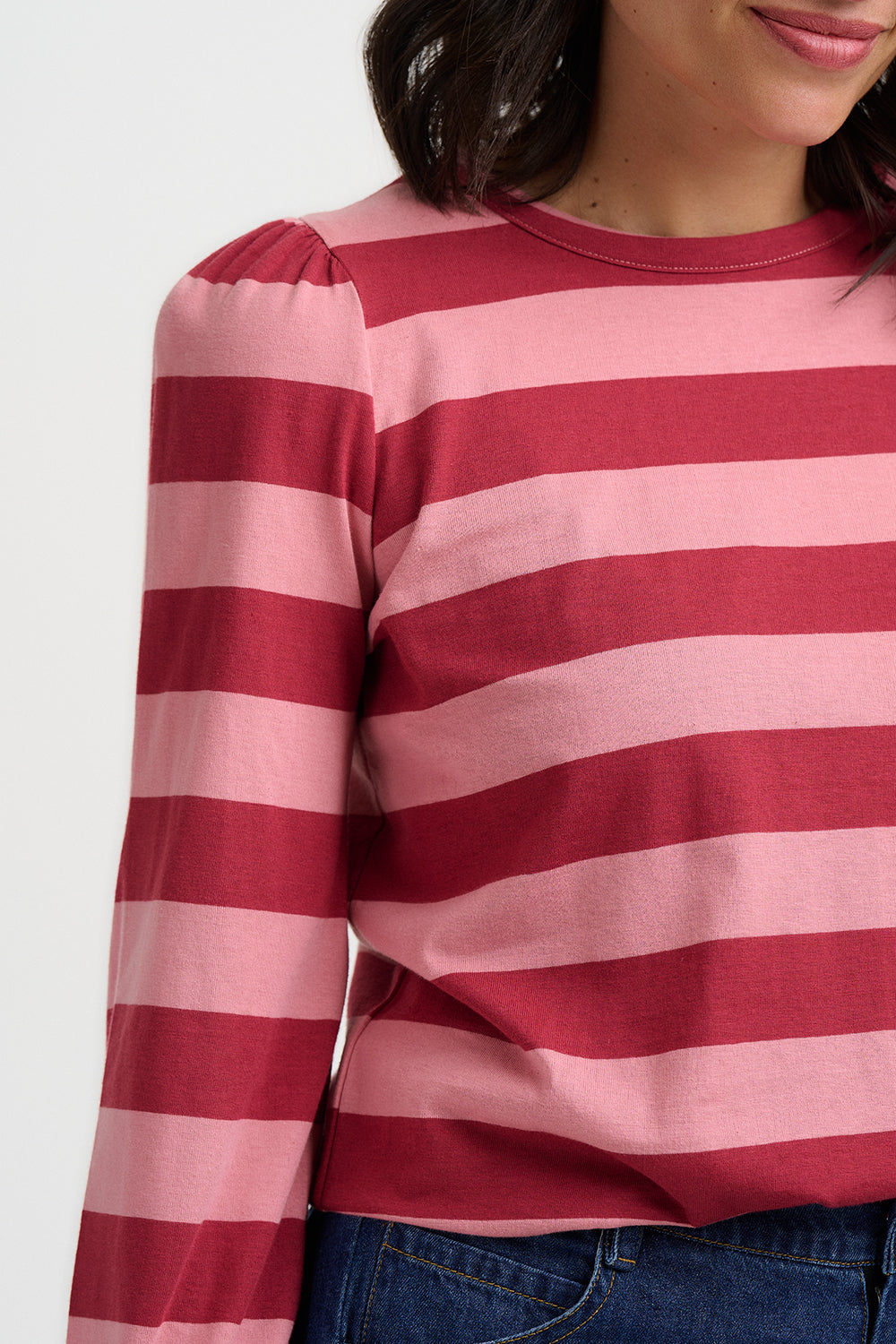 Person wearing a red and pink striped long-sleeve shirt against a white background