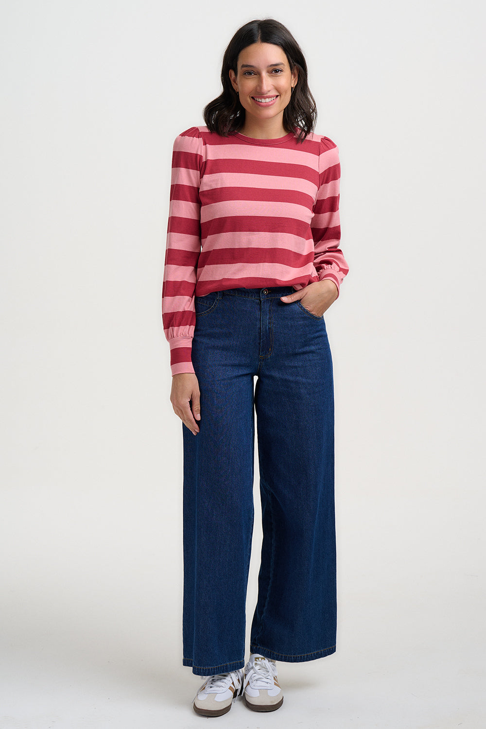 Woman wearing a red and white striped sweater and blue jeans on a white background
