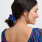 Woman with a blue hair tie in her ponytail wearing a colorful dress on a white background