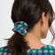 Person wearing a green scrunchie with pink hearts in their hair against a white background