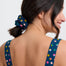 Woman wearing a polka dot dress with a matching scrunchie on a white background