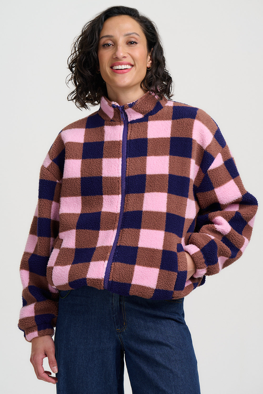 Woman wearing a checkered jacket with pink, blue, and brown colors on a white background